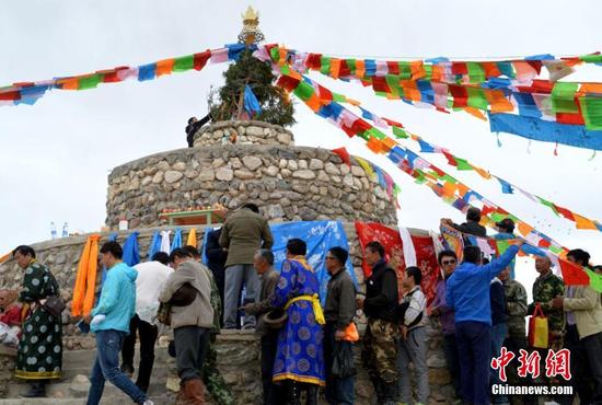 近日，甘肃肃北蒙古族自治县石包城乡举行祭祀“梦柯阿木古楞”敖包暨那达慕大会。传统祭敖包活动按照焚香点火、颂词念经、敬献贡品等流程进行，牧民们围绕敖包从左向右转三圈，并将奶茶、点心、糖块洒向敖包，祈福纳祥。随后那达慕大会拉开序幕，举办了“男儿三技艺”赛马、摔跤、射箭等蒙古族传统体育竞技比赛项目，展示了游牧文化的魅力。活动吸引了周边300多名牧民群众参加。图为民众祭祀敖包活动。佟格勒格