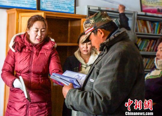 图为肃北县图书馆馆员给村里群众讲解蒙文图书。　郑磊斌　摄
