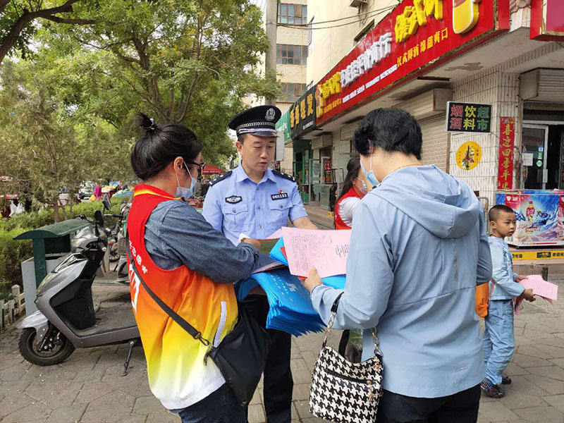 图为:社区民警和志愿者在人员较多的市场宣传防电诈知识.jpg